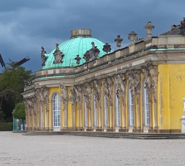 Seitenansicht vom Schloss Sanssouci mit der historischen Mühle im Hintergrund