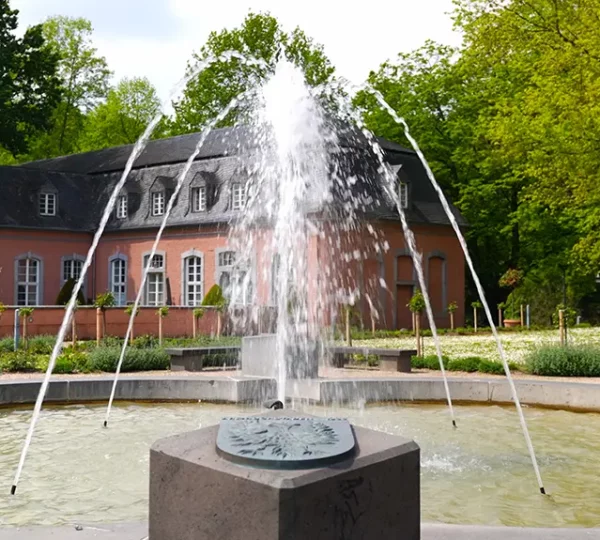 Teil vom Westflügel der Vorburg vom Schloss Wickrath mit Brunnen im Vordergrund